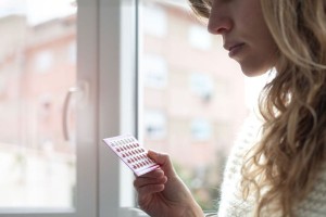 Young woman holding contraceptive pills (Getty Images/Cris Cantón)