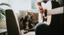 Dog looking at owner play the guitar